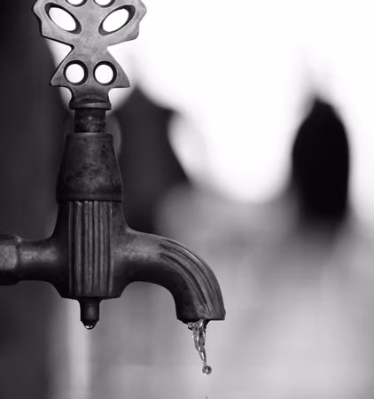 Primer plano de una llave antigua de la que cae una gota de agua; imagen ilustrativa sobre presión y cuidado del agua, sin representar una ubicación específica.