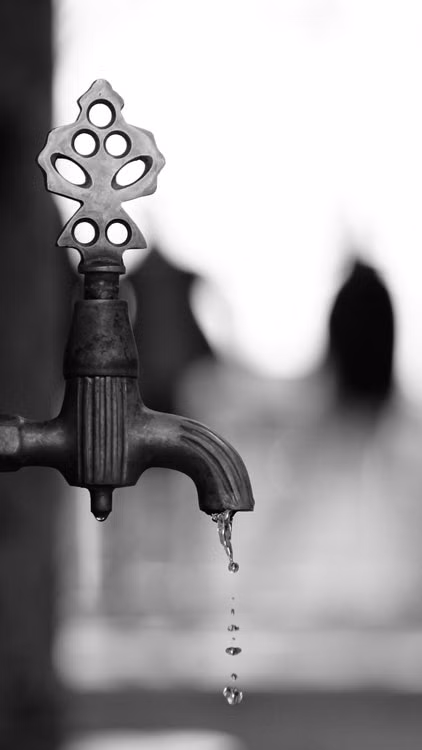 Primer plano de una llave antigua de la que cae una gota de agua; imagen ilustrativa sobre presión y cuidado del agua, sin representar una ubicación específica.