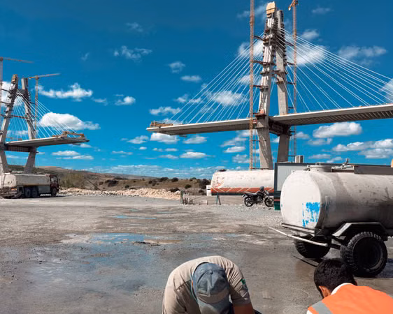 Vista de una obra de infraestructura vial con un tramo elevado y estructuras en construcción bajo cielo azul; imagen ilustrativa sobre inversión pública, sin identificar una obra específica.