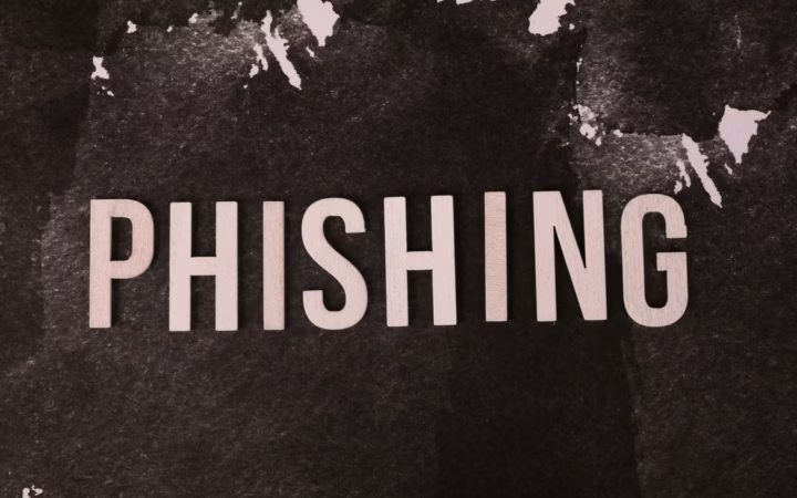 Mano sostiene un teléfono con un mensaje de alerta genérico en pantalla; recurso ilustrativo sobre prevención de phishing, sin mostrar una institución real.
