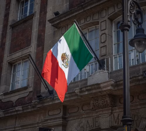 Bandera de México frente a un edificio público; imagen ilustrativa sobre el proceso electoral, sin alusión a partido o candidatura.