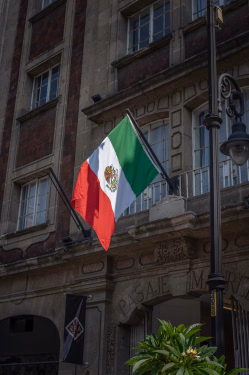 Bandera de México frente a un edificio público; imagen ilustrativa sobre el proceso electoral, sin alusión a partido o candidatura.