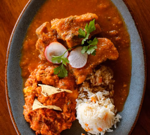 Plato de mole oscuro con guarnición; imagen editorial sobre la cocina mexicana tradicional.